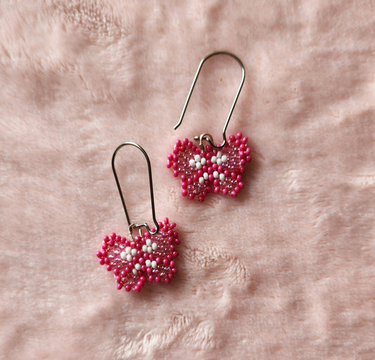 Fully beaded dark pink, light pink, and white seed bead earrings on kidney hooks, on a pink furry background.